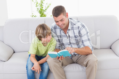 Father reading story for boy on sofa