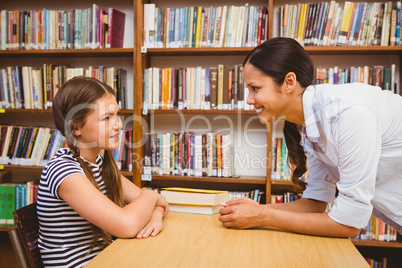 Female teacher and little girl in library