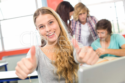 Female student gesturing thumbs up in classroom