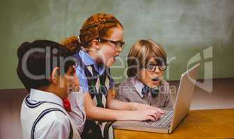 Shocked little school kids using laptop