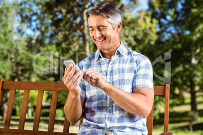 Man sitting on park bench with phone