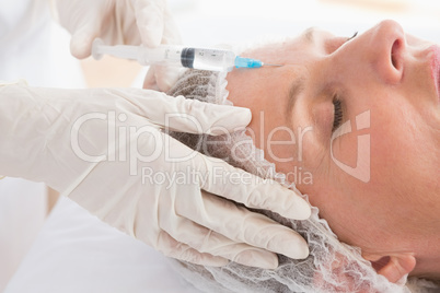 Woman receiving botox injection on her forehead