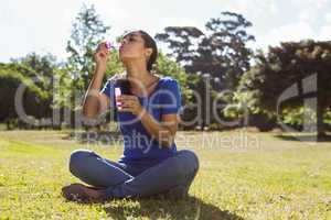 Pretty woman blowing bubbles in the park