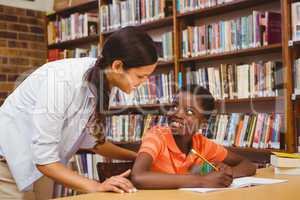 Teacher assisting boy with homework in library