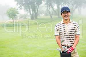 Cheerful golfer smiling at camera holding golf bag