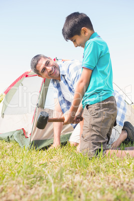 Father and son pitching their tent