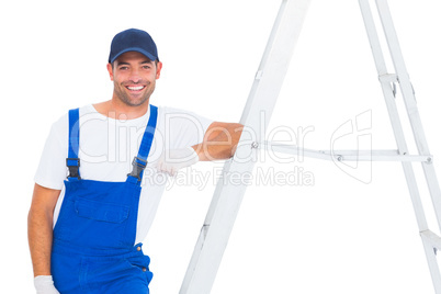 Handyman in overalls leaning on ladder