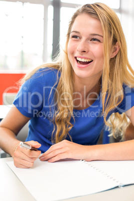 Cheerful female student writing notes in classroom