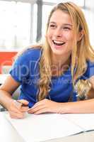 Cheerful female student writing notes in classroom