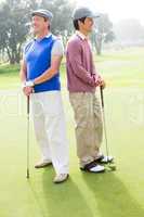 Golfing friends smiling and holding clubs