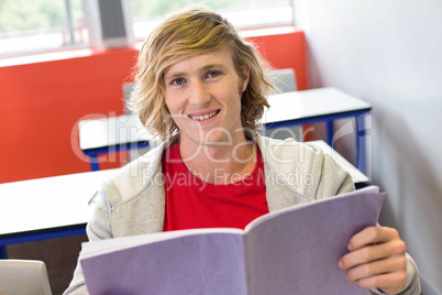 Male student reading notes in classroom