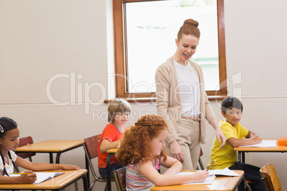 Pretty teacher helping pupils in classroom