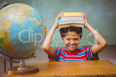 Little boy holding books over head in classroom
