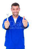 Smiling mechanic holding spanner while gesturing thumbs up