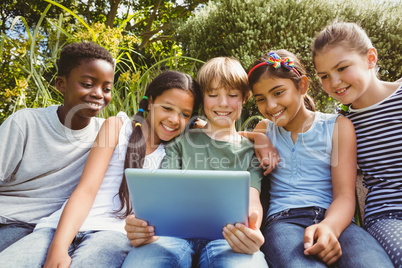 Happy children using digital tablet at park