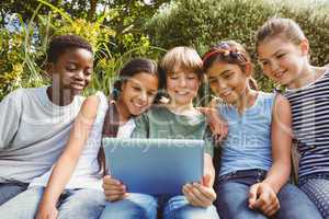 Happy children using digital tablet at park