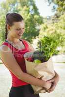 Fit woman holding bag of healthy groceries