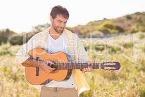 Happy man smiling at camera playing guitar