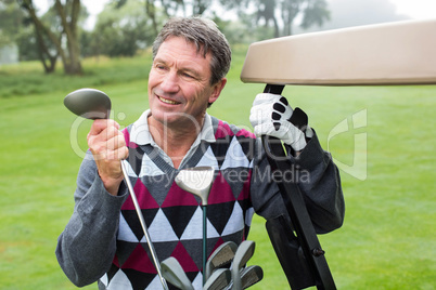 Happy golfer beside his golf buggy