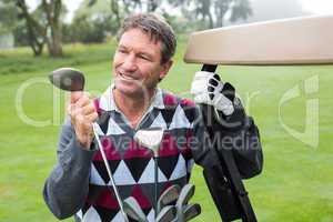 Happy golfer beside his golf buggy