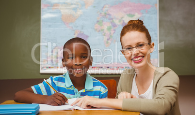 Teacher assisting little boy with homework in classroom