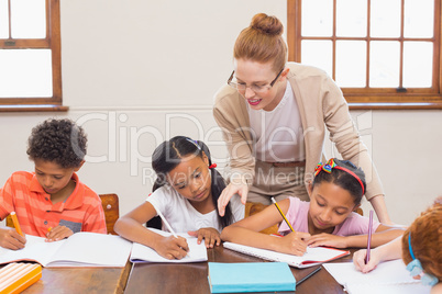 Cute pupils getting help from teacher in classroom