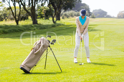 Female concentrating golfer teeing off