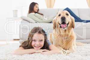 Girl with dog lying on rug at home