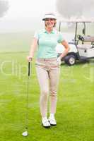 Happy golfer with golf buggy behind