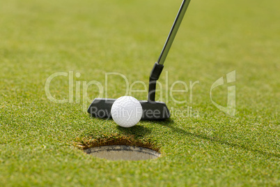 Golf club putting ball at the hole