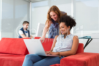 Creative team using laptop on sofa