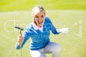 Excited lady golfer cheering on putting green