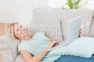 Beautiful woman using laptop while lying on sofa