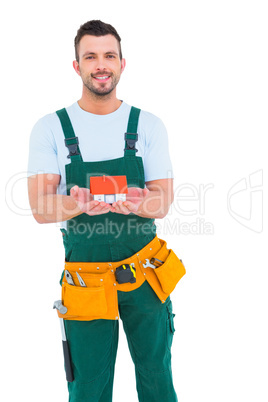 Happy construction worker holding house model