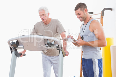 Senior man on treadmill with trainer