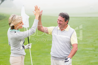 Golfing couple high fiving