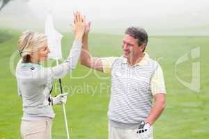 Golfing couple high fiving