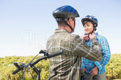 Father attaching his son cycling helmet