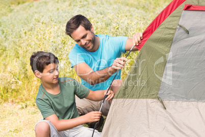 Father and son pitching their tent