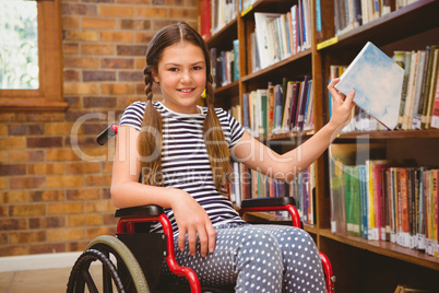 Girl in wheelchair selecting book in library