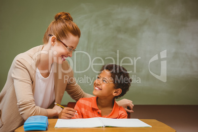 Teacher assisting little boy with homework in classroom