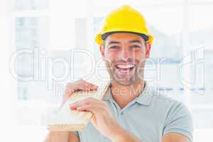 Cheerful male carpenter carrying planks
