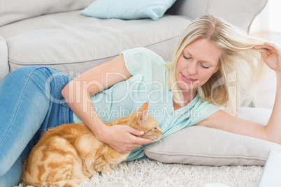 Woman stroking cat while playing with hair on rug