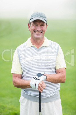 Cheerful golfer smiling at camera holding his club