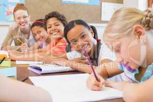 Cute pupils writing at desk in classroom