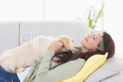 Woman with puppy lying on sofa