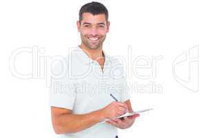 Smiling male handyman writing on clipboard