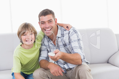 Happy father and son using remote control on sofa