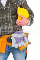 Manual worker wearing tool belt while holding helmet