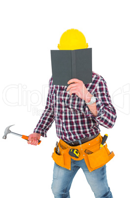 Handyman reading diary and holding hammer